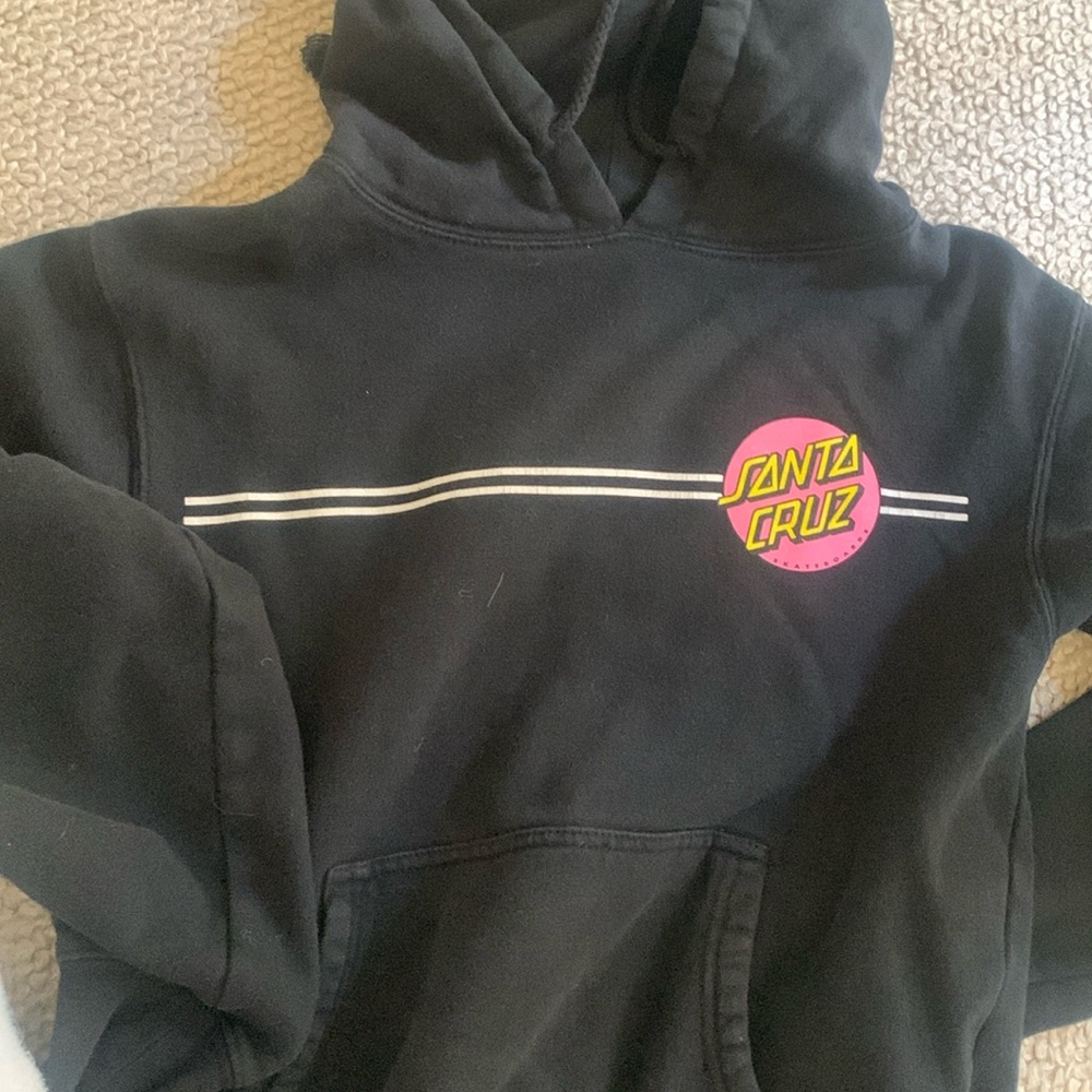 Santa Cruz black and pink sweater. It fits 10/12 yo in good used condition.